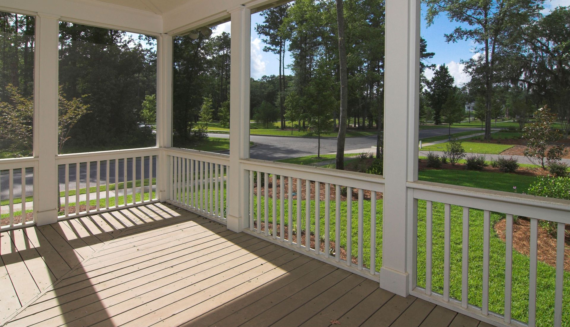 Screened porch overlooking a green lawn and street; sunny day.