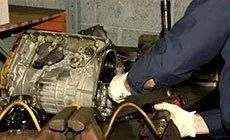 Mechanic working on a large metal gearbox with gloves in an industrial workshop