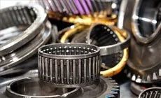 Assorted metal bearings and rings in close-up, including a cylindrical roller bearing in the center