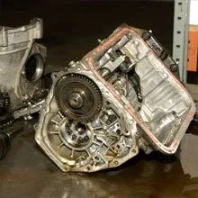 Damaged car transmission on the floor, with gears and housing exposed.