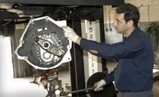 Mechanic inspecting a car transmission under a lift in a garage