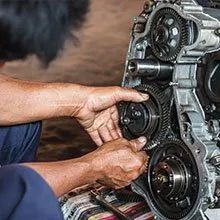 Mechanic hands adjusting a car engine’s timing belt and pulleys during repair