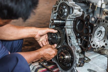 Mechanic’s hands removing a gear from an engine block on a workbench