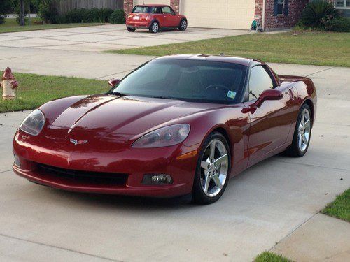 A red sports car is parked in a driveway in front of a garage.