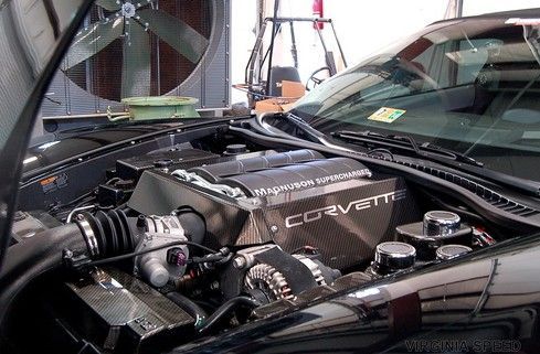 The engine of a black corvette with the hood open