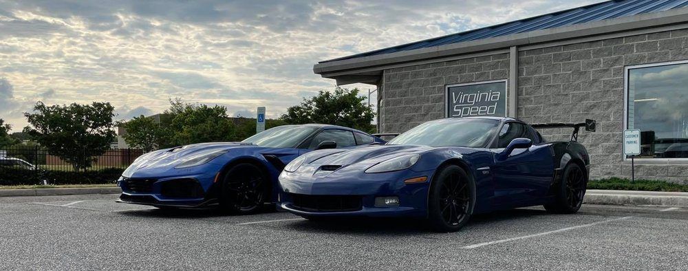 Two blue sports cars are parked in front of a building.