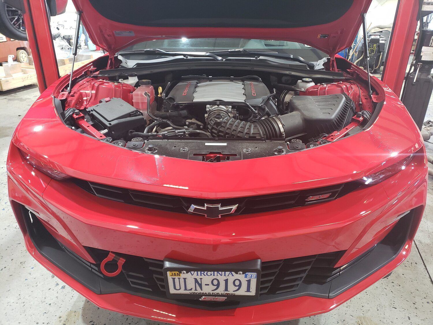 A red car with the hood up and a license plate that says uln 9191