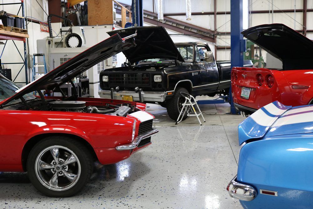 A red car is parked in a garage with its hood up