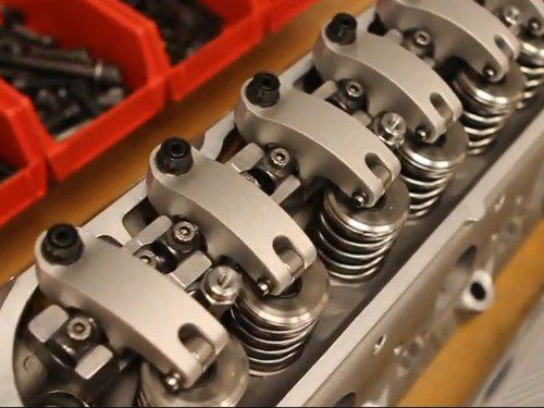 A close up of a cylinder head with red bins in the background