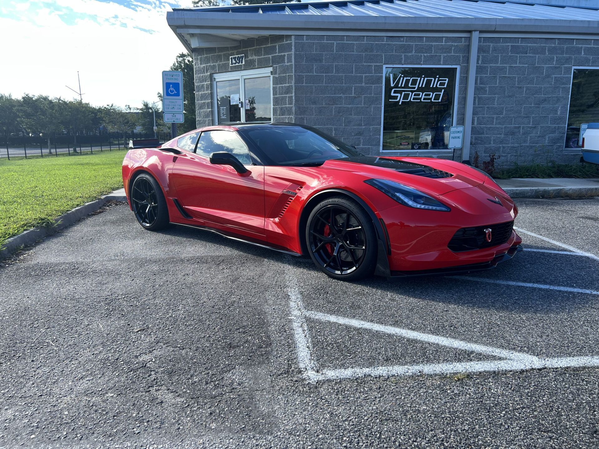 A red corvette is parked in a parking lot in front of a building.