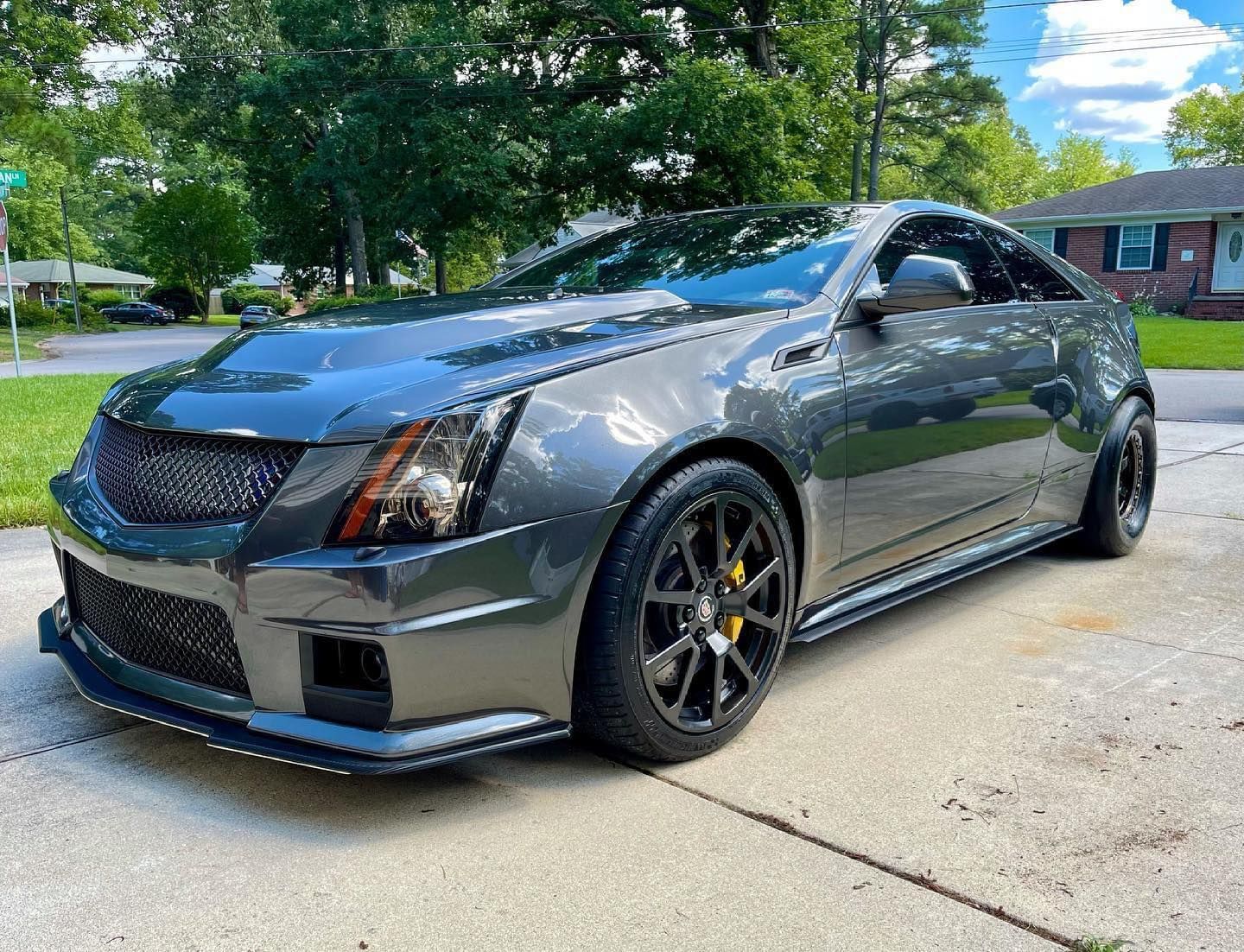 A gray car is parked in a driveway in front of a house.