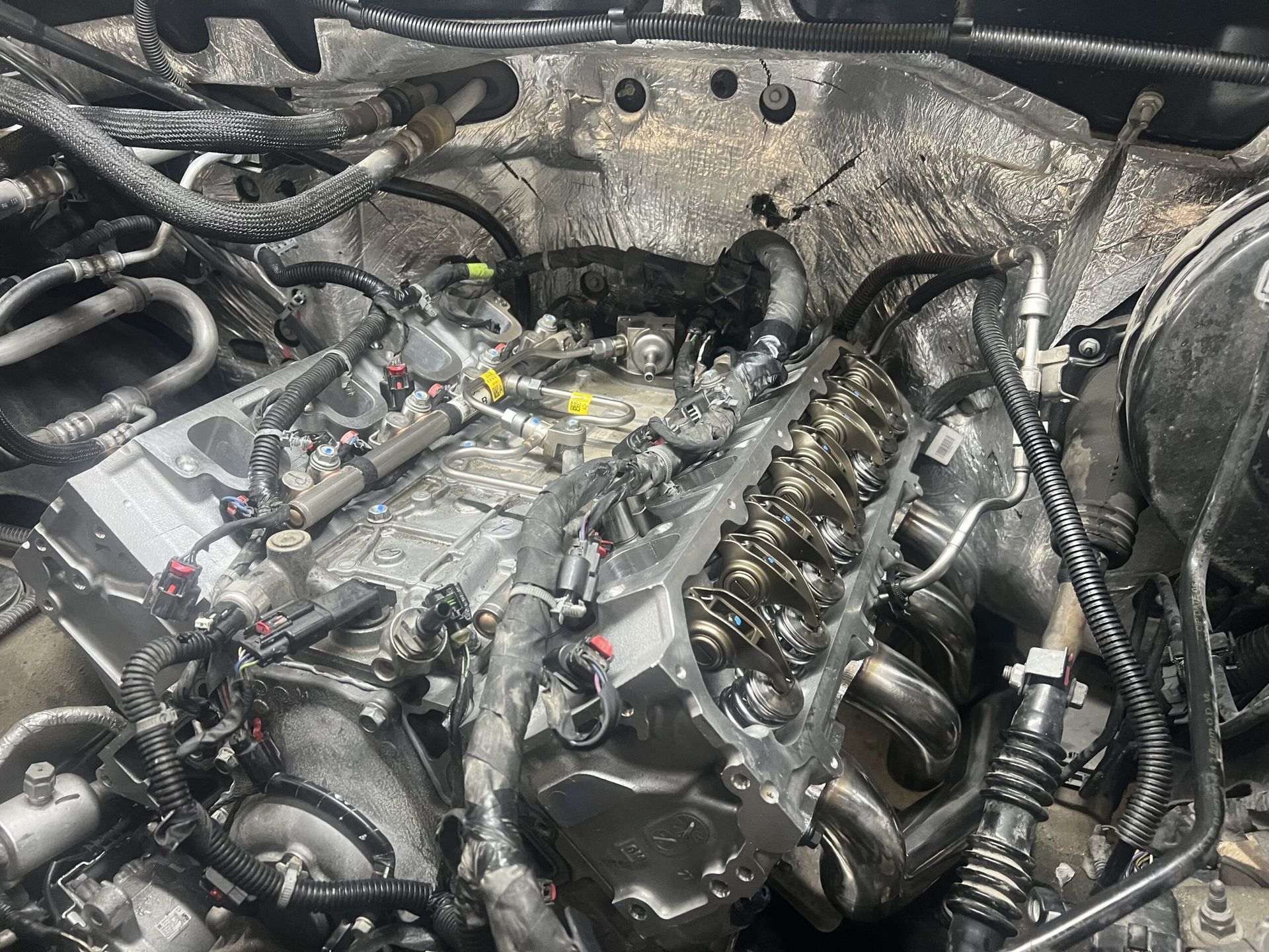 A close up of a car engine with a lot of wires coming out of it.