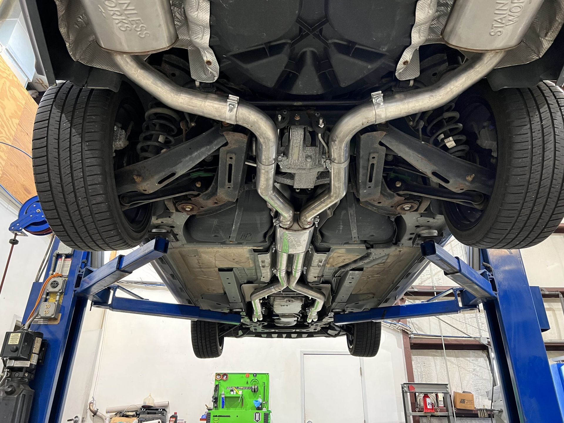 The underside of a car on a lift in a garage.
