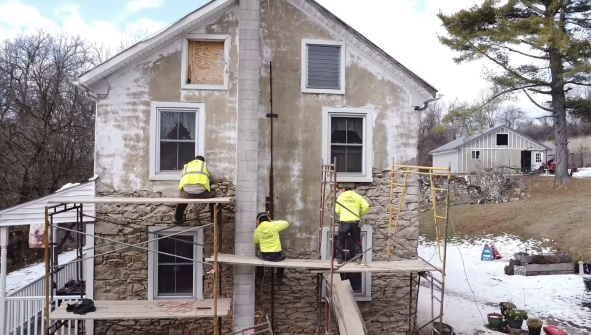 A group of men are working on the side of a house.