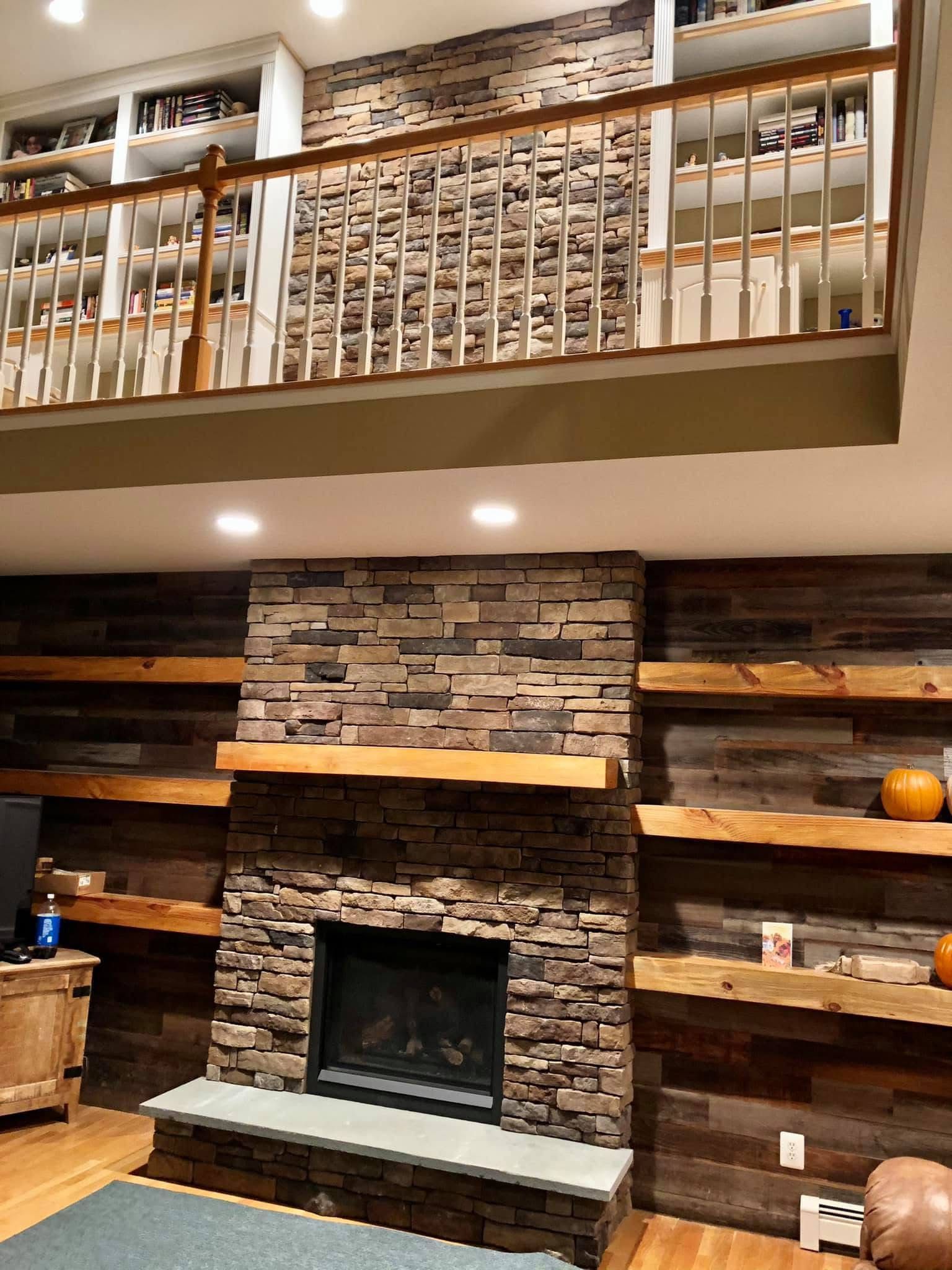 A living room with a brick fireplace and wooden shelves.