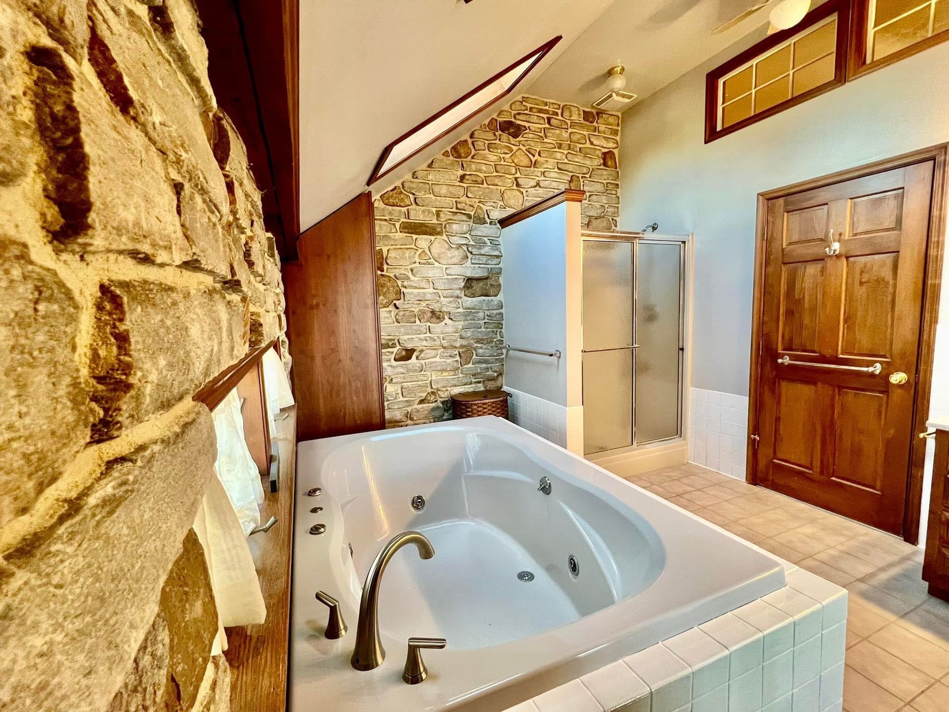 A bathroom with a jacuzzi tub and a stone wall.