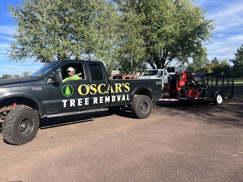 An oscar 's tree removal truck is parked in a parking lot.