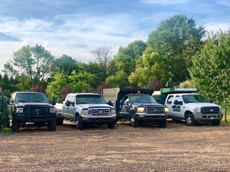 A group of trucks are parked in a gravel lot.