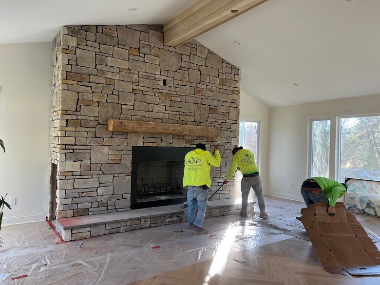 Two men are working on a stone fireplace in a living room