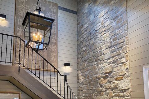 A staircase with a lantern hanging from the railing and a stone wall.