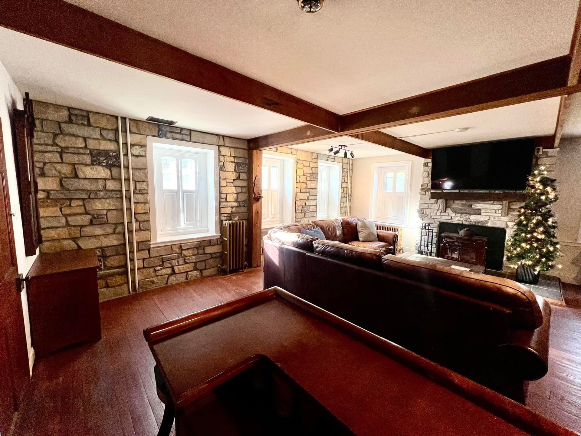 A living room with a pool table , couch , fireplace and christmas tree.