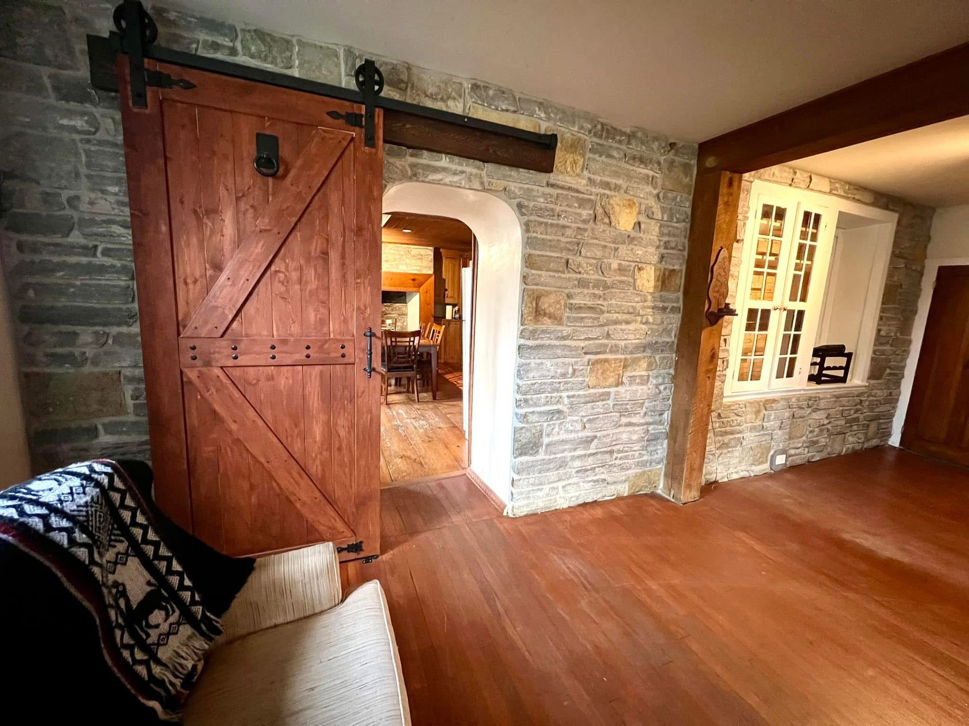 A living room with a wooden sliding barn door and a stone wall.
