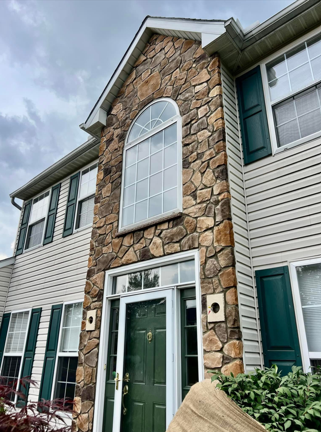 The front of a house with a stone facade and green shutters.