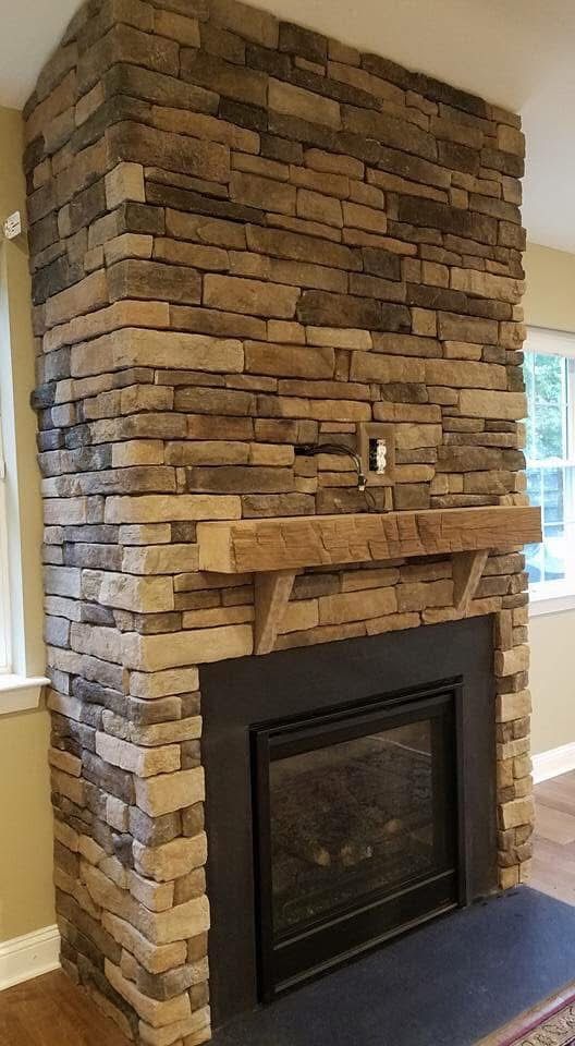 A large stone fireplace with a mantle in a living room.