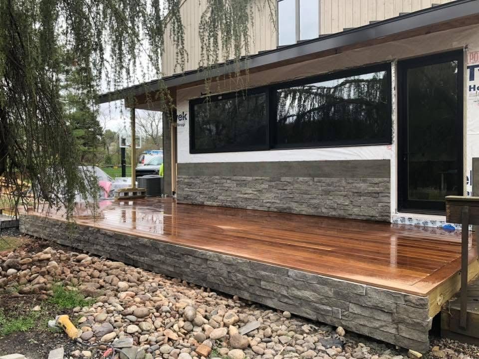 A wooden deck is sitting in front of a house.