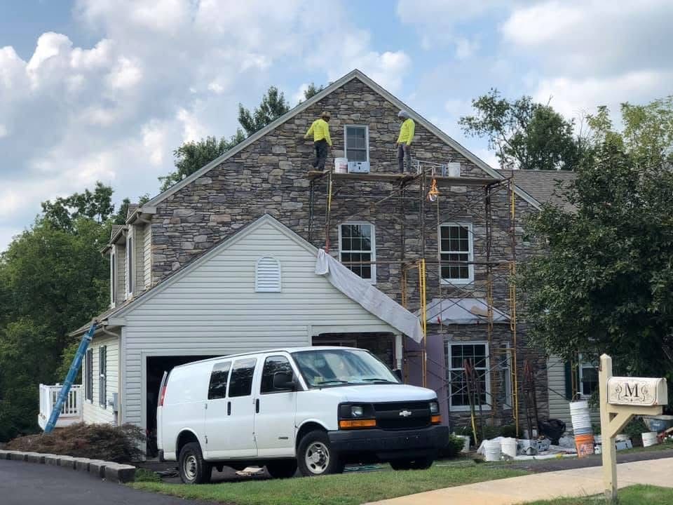 A white van is parked in front of a house that is being painted.