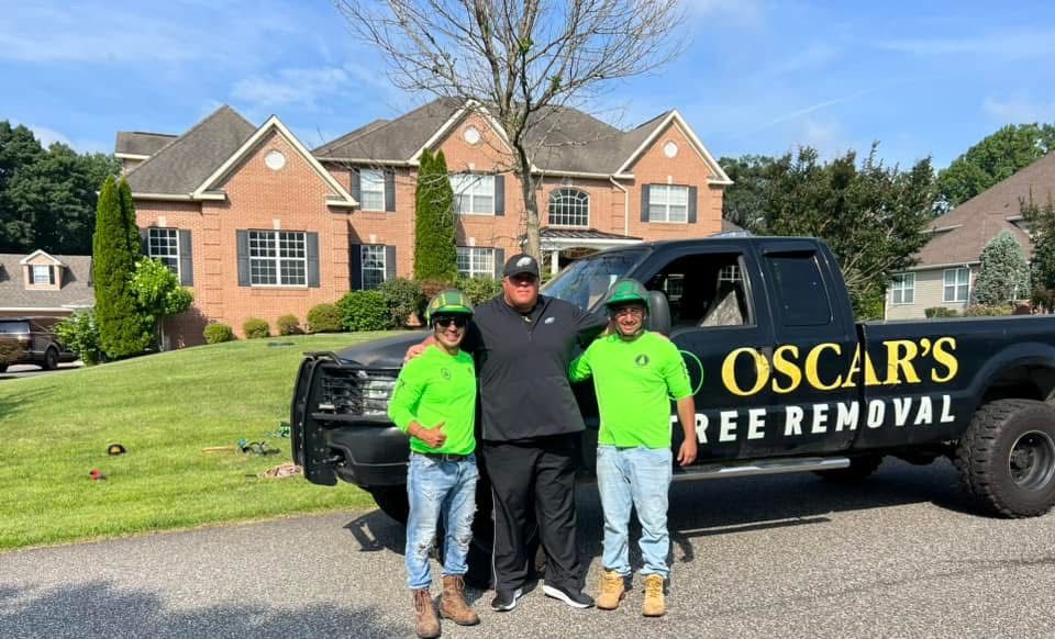Three people are standing in front of a truck that says oscar 's tree removal.