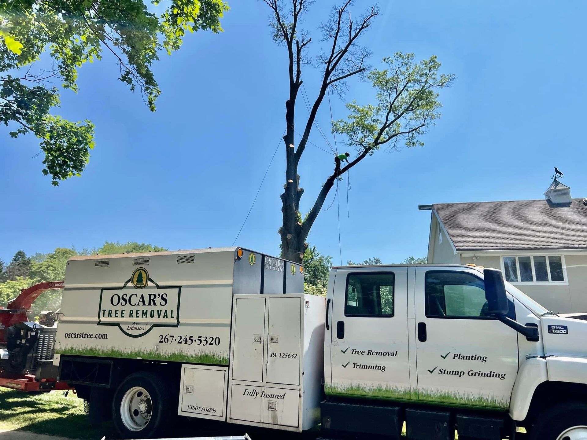 A white oscar 's tree service truck is parked in front of a house.