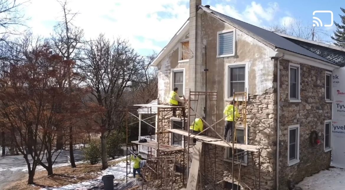A group of men are working on a stone house.