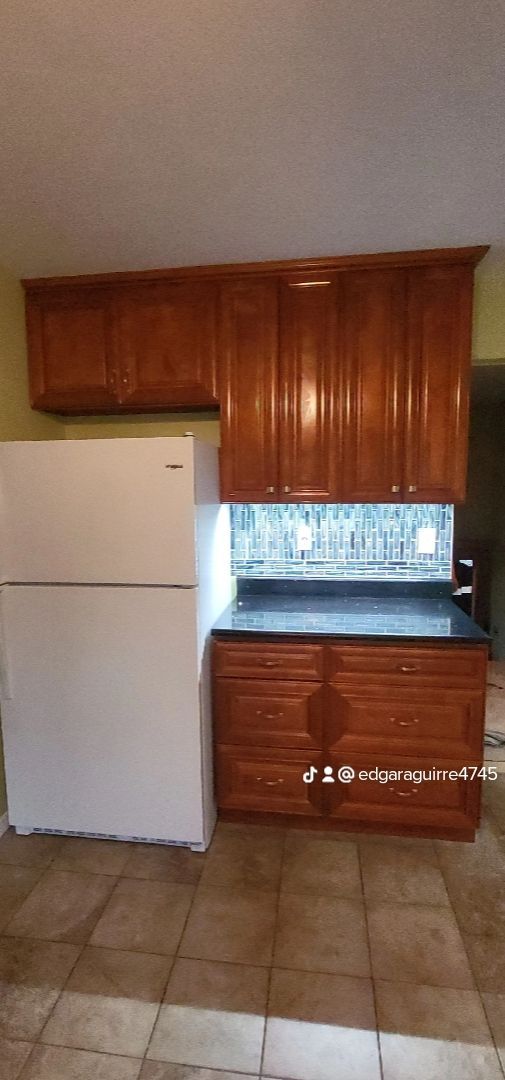 a kitchen with wooden cabinets and a white refrigerator view