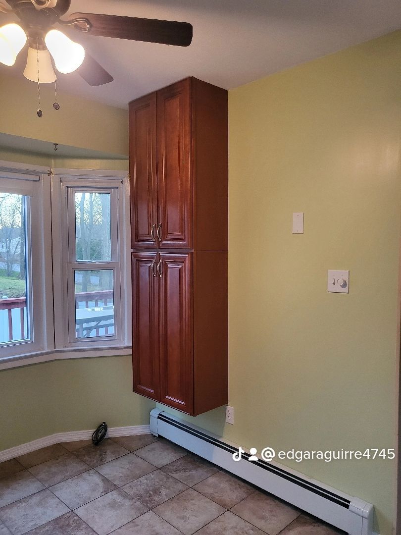 a kitchen with a ceiling fan , cabinets, and a window