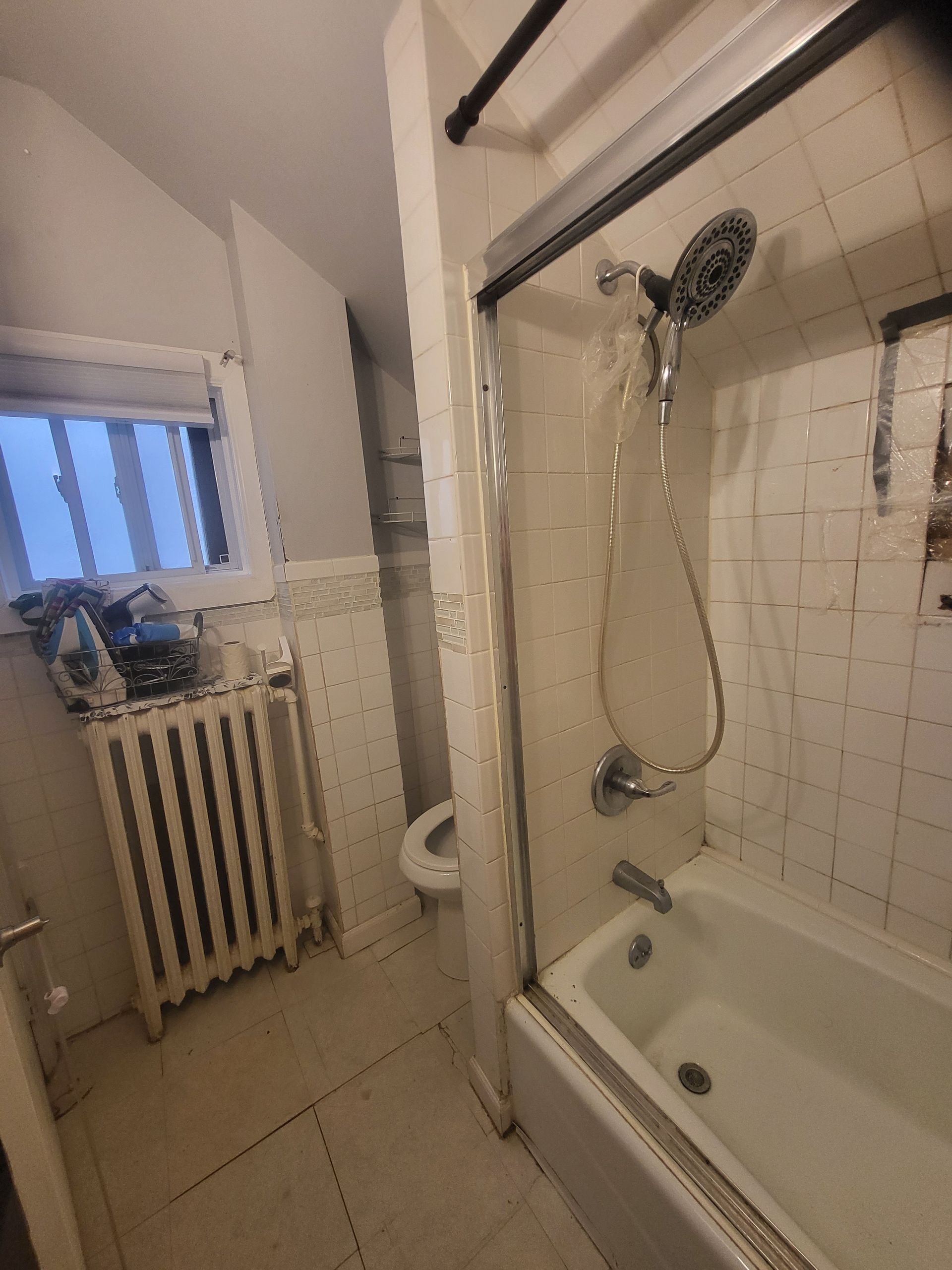 a bathroom with a tub, shower, toilet, and radiator