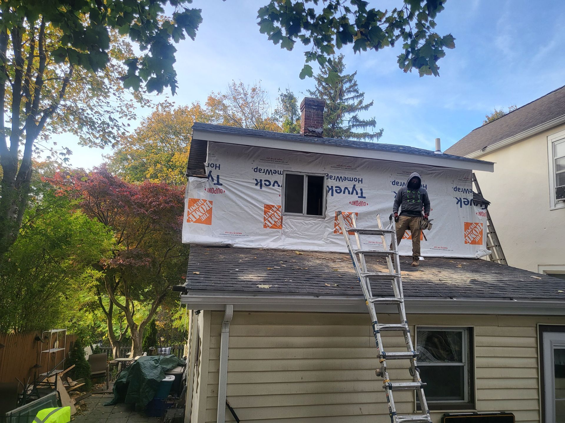 a man is standing on a ladder on the roof of a house