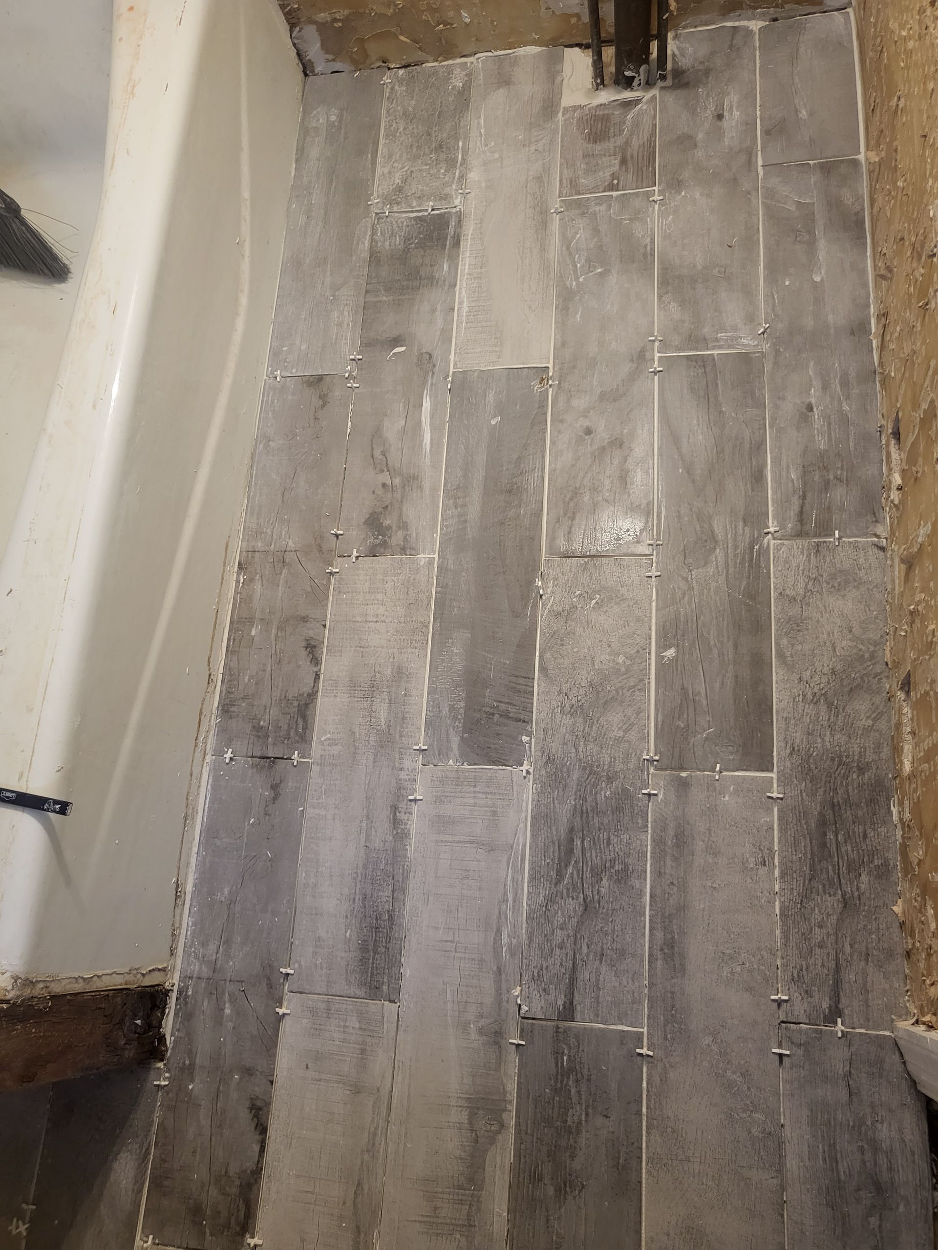 a bathroom floor with tiles and a bathtub in the background