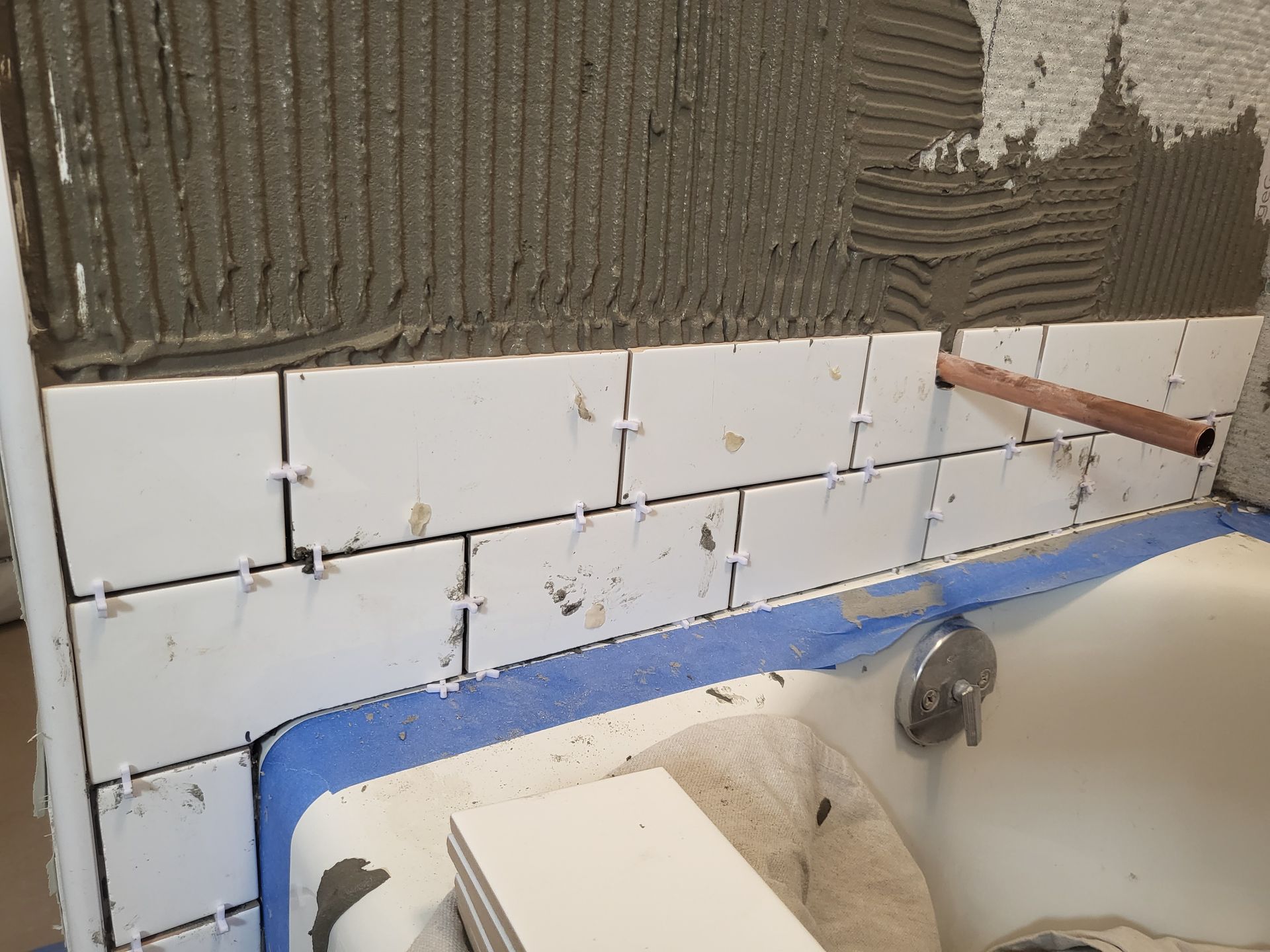 a bathroom wall is being tiled with white tiles
