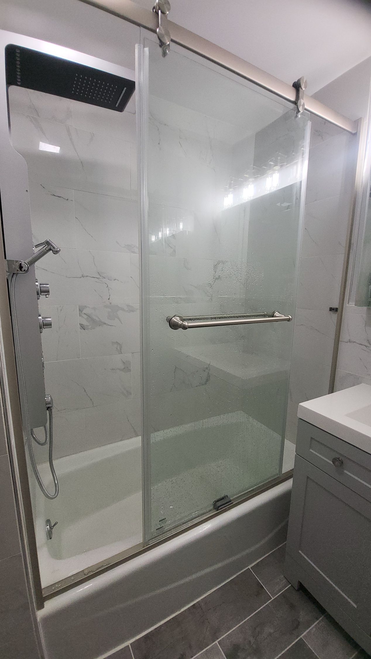 a bathroom with a sliding glass shower door and a bathtub