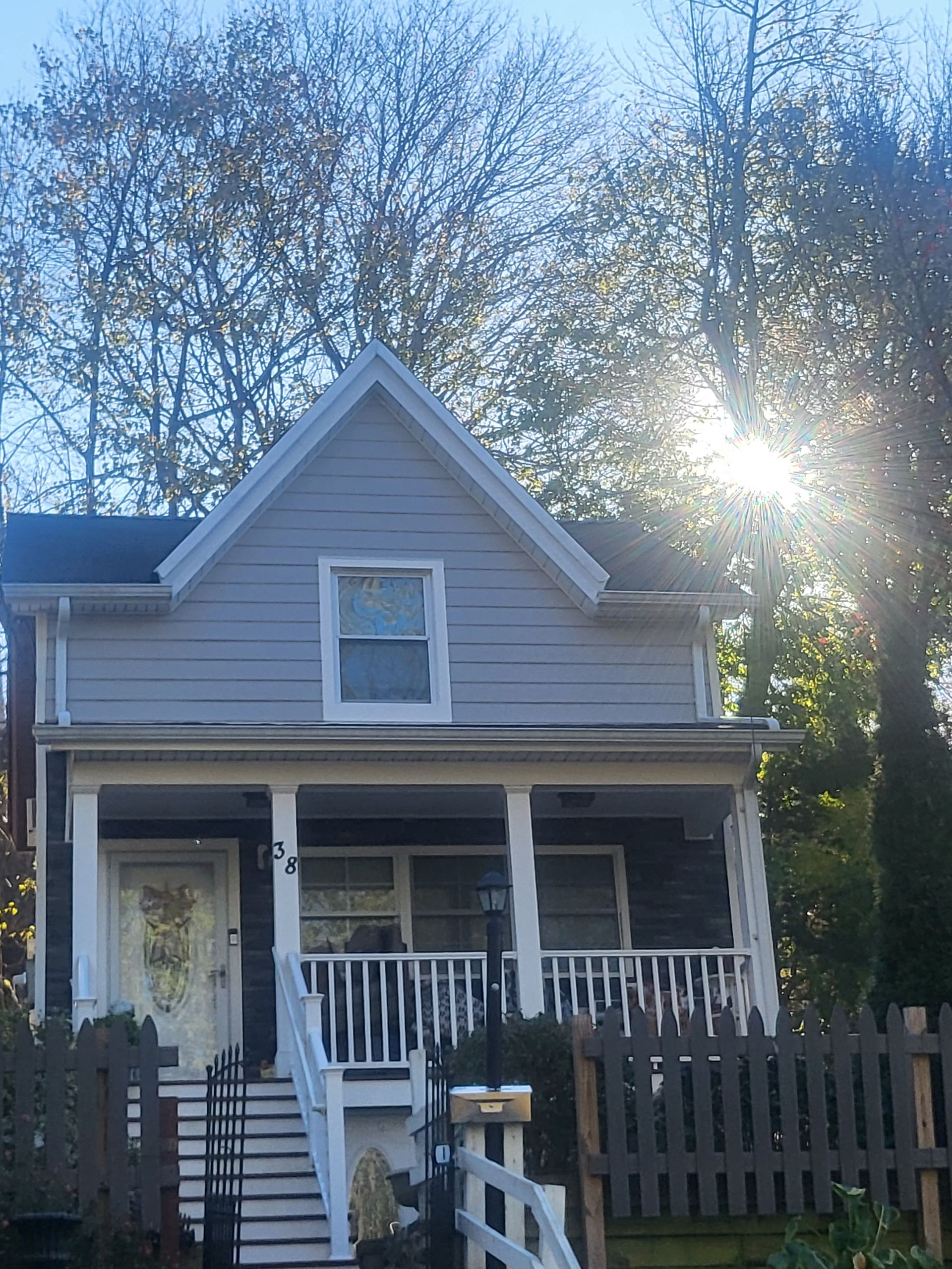 a house with a porch and a fence in front of it