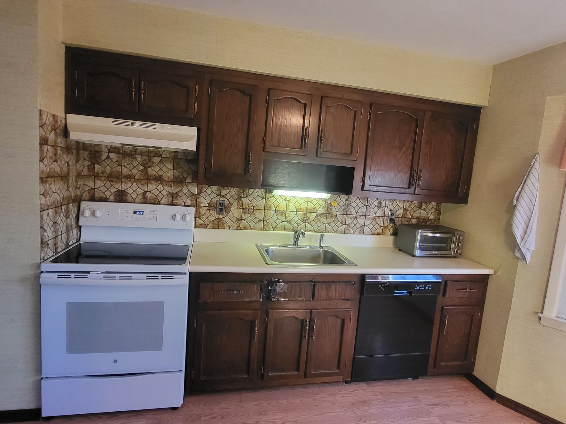 a kitchen with a stove, sink, and dishwasher
