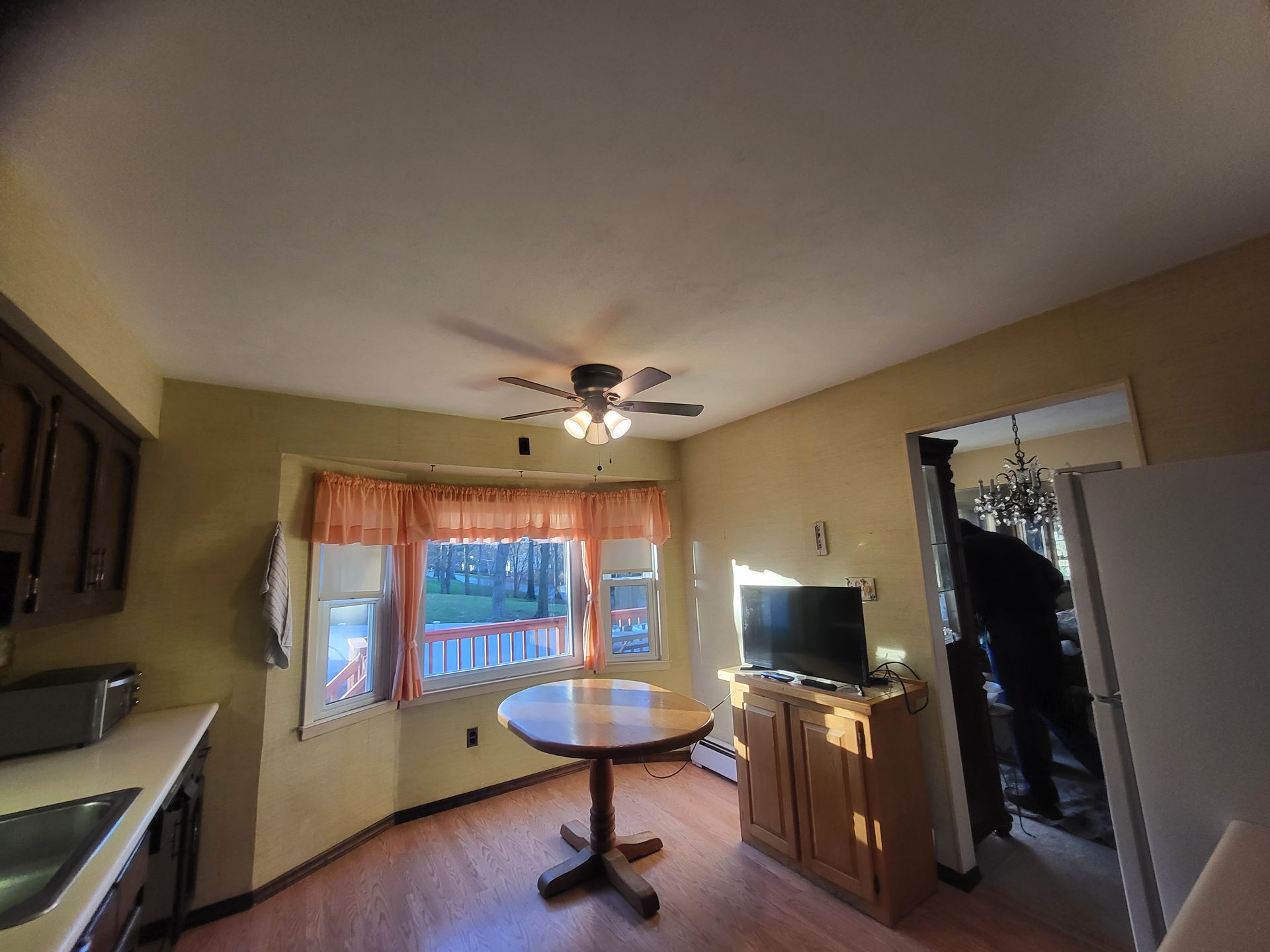 a kitchen with a table, television, and ceiling fan