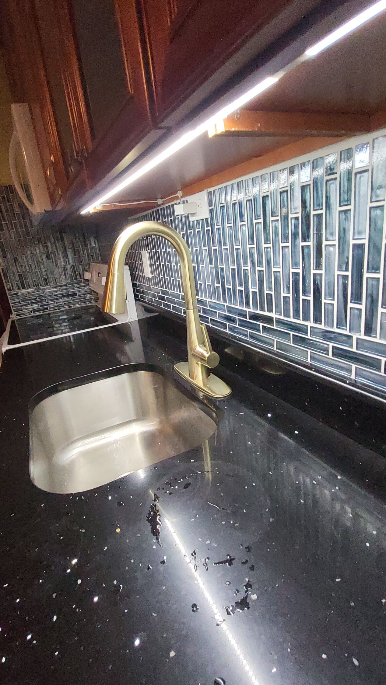 a kitchen sink with a gold faucet on a black counter top