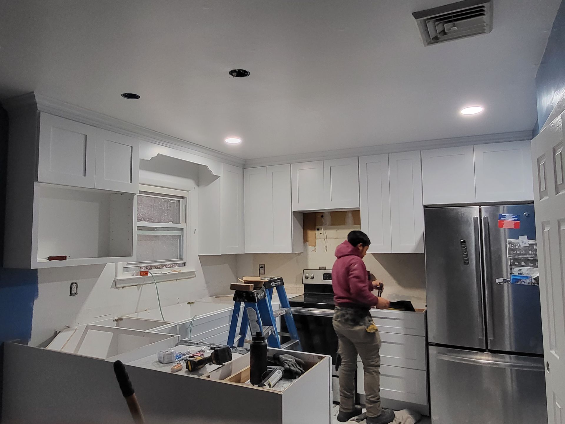a man is working in a kitchen with white cabinets and stainless steel appliances