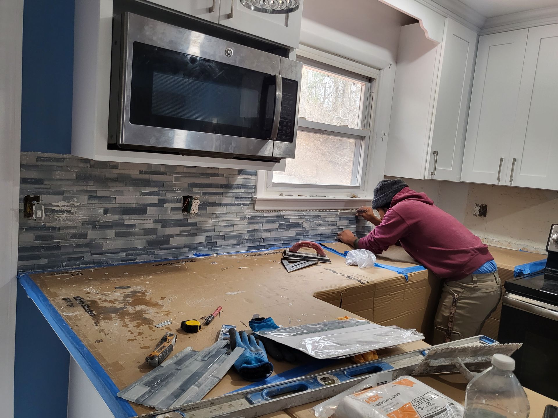 a man is working on a kitchen counter with a microwave