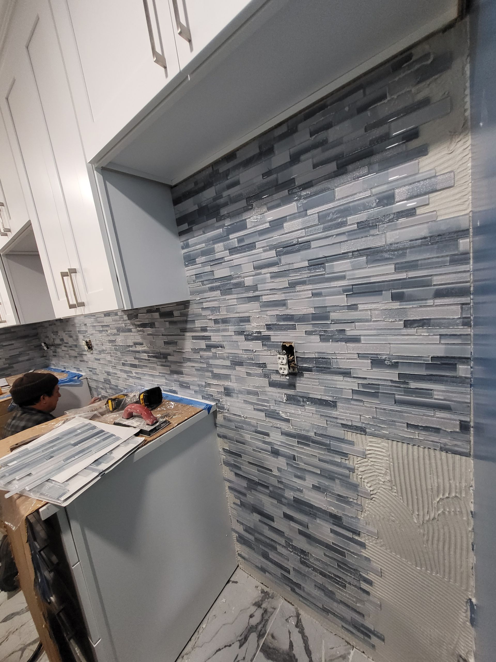 a man is installing tiles on the wall of a kitchen