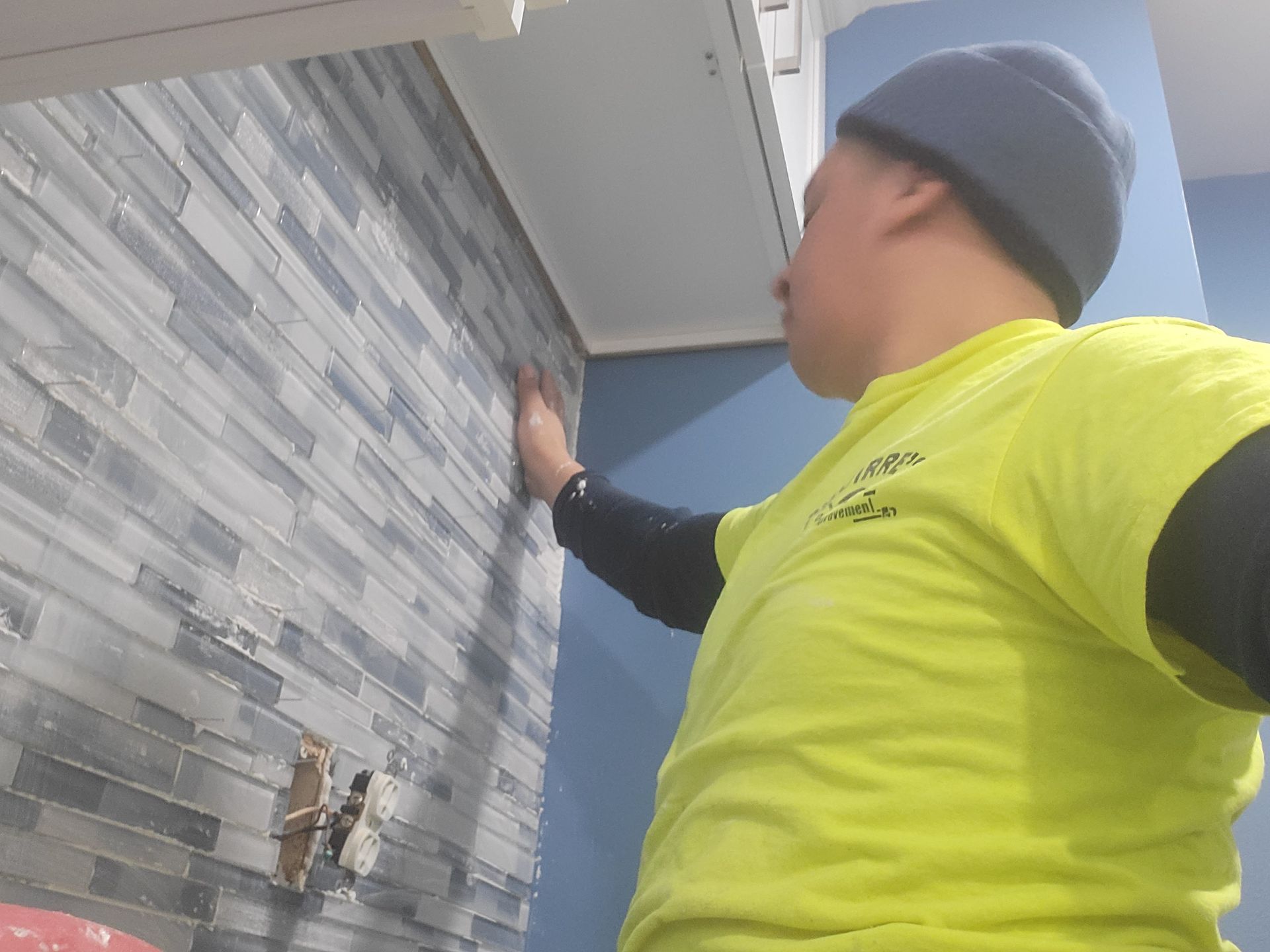 a man in a yellow-green shirt is working on a wall