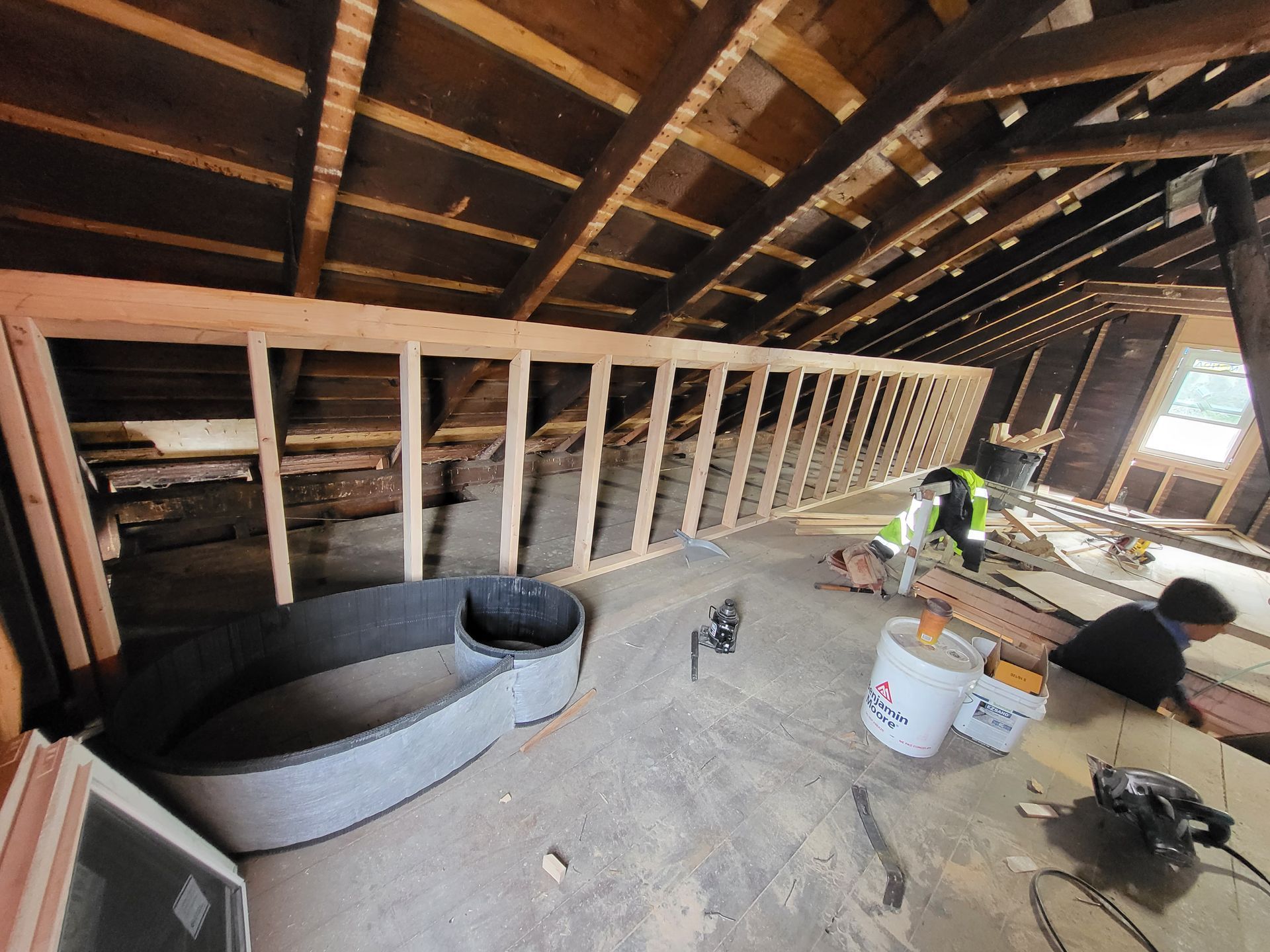 a man is working on a wooden structure in an attic