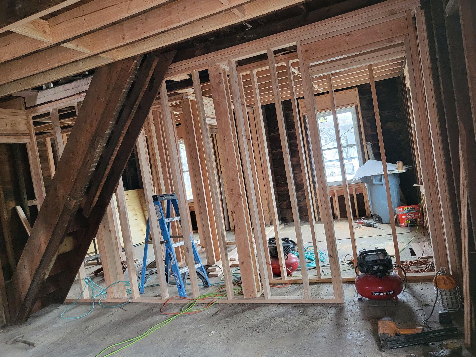 a room under construction with a ladder, air compressor, and measuring tape